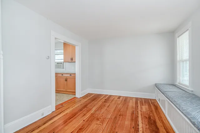 a view of empty room with wooden floor and kitchen