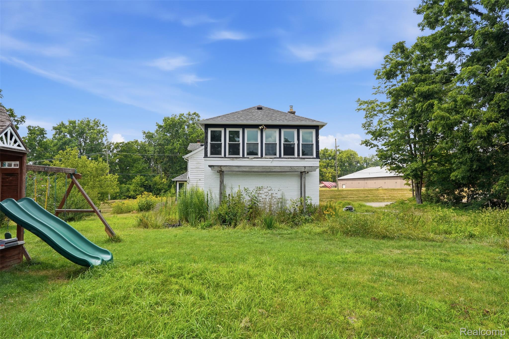 31000 Drake Road Farmington, MI 48331 - Photo 32 of 44 Expansive green space featuring a two-story structure with a distinctive upper level, multiple windows, and a dark shingled roof