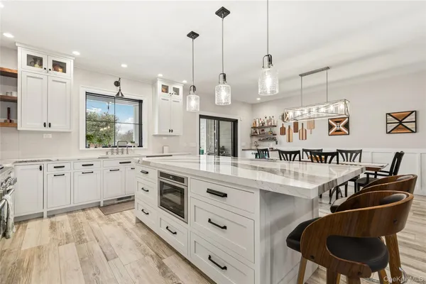 a kitchen with stainless steel appliances granite countertop a sink a stove a refrigerator and island with wooden floor