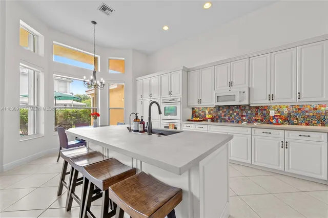 a kitchen with stainless steel appliances granite countertop a table chairs sink and white cabinets