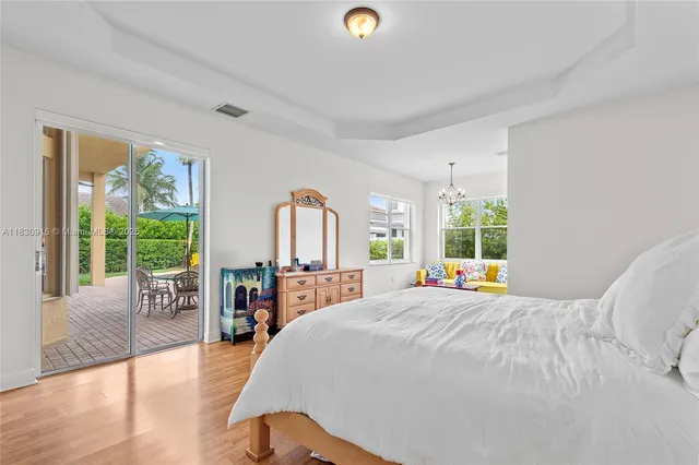 a bed sitting in a spacious bedroom next to a large window with table and chairs