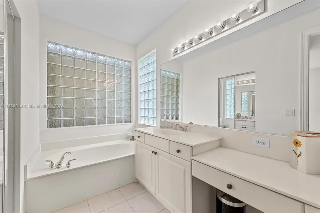 a bathroom with a tub a sink and mirror