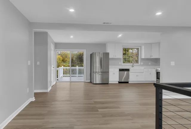 an empty room with wooden floor ceiling fan and windows