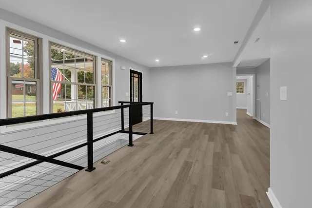 a view of an empty room with window and wooden floor