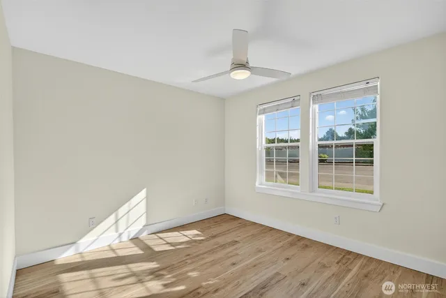 a view of an empty room with wooden floor and a window