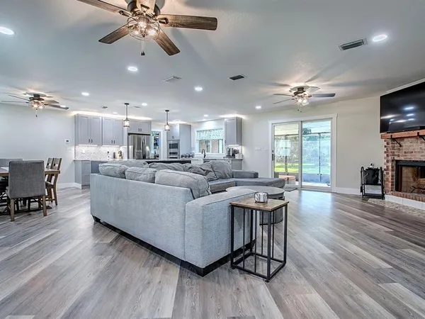 a living room with stainless steel appliances lots of furniture and kitchen view