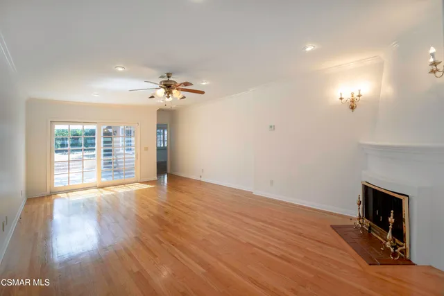 a view of an empty room with wooden floor and a fireplace