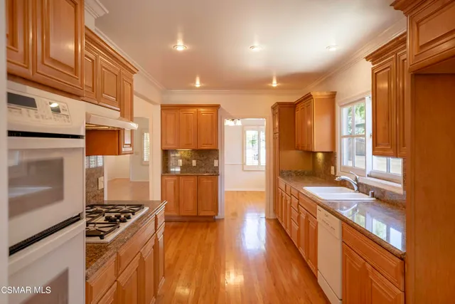 a kitchen with stainless steel appliances granite countertop a refrigerator a stove and a wooden floors
