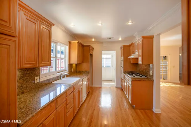 a view of a kitchen with kitchen island granite countertop wooden floors and a sink