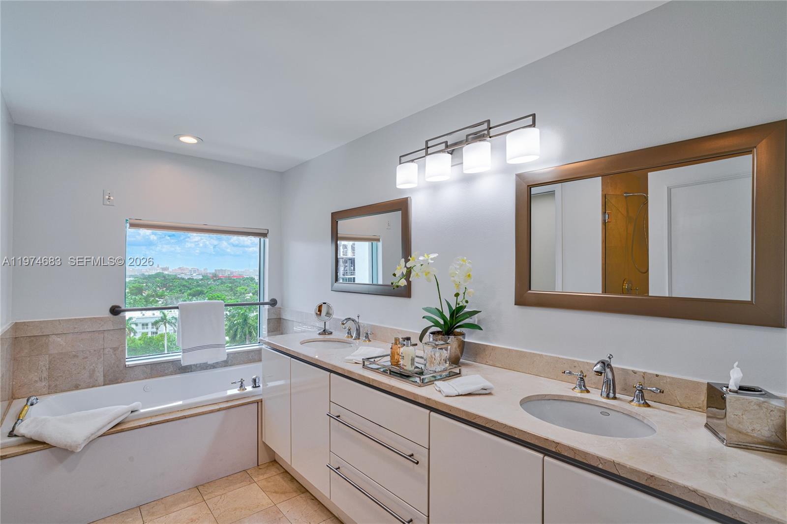 3400 Southwest 27th Avenue, Unit 906 Miami, FL 33133 - Photo 15 of 35 a bathroom with a granite countertop sink mirror and a bathtub