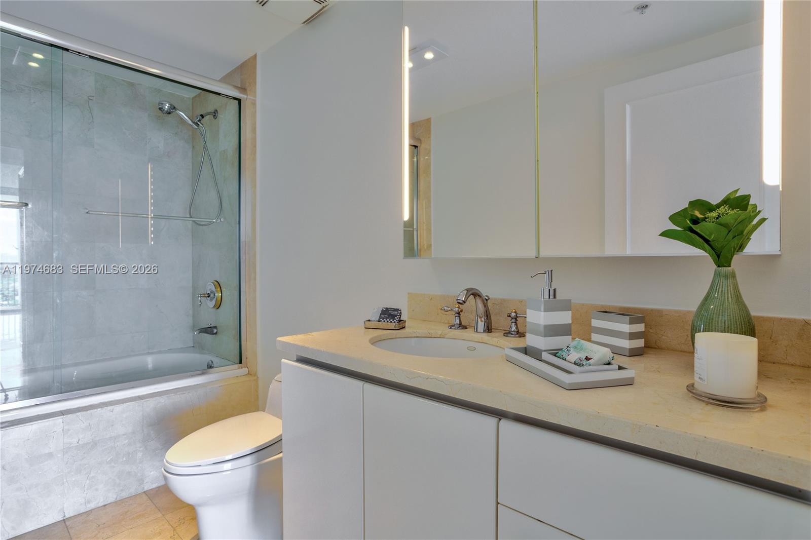 3400 Southwest 27th Avenue, Unit 906 Miami, FL 33133 - Photo 19 of 35 a bathroom with a granite countertop sink a toilet and shower