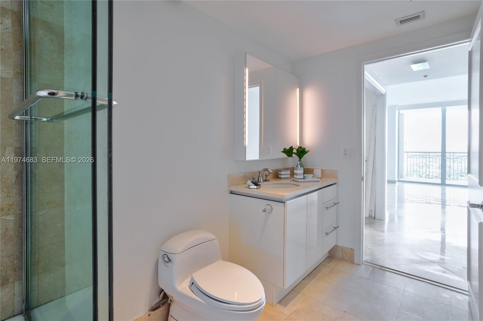 3400 Southwest 27th Avenue, Unit 906 Miami, FL 33133 - Photo 20 of 35 a bathroom with a toilet a sink a mirror a vanity and window