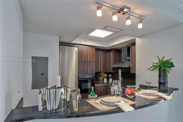 a kitchen with stainless steel appliances granite countertop a sink a stove and a wooden cabinets