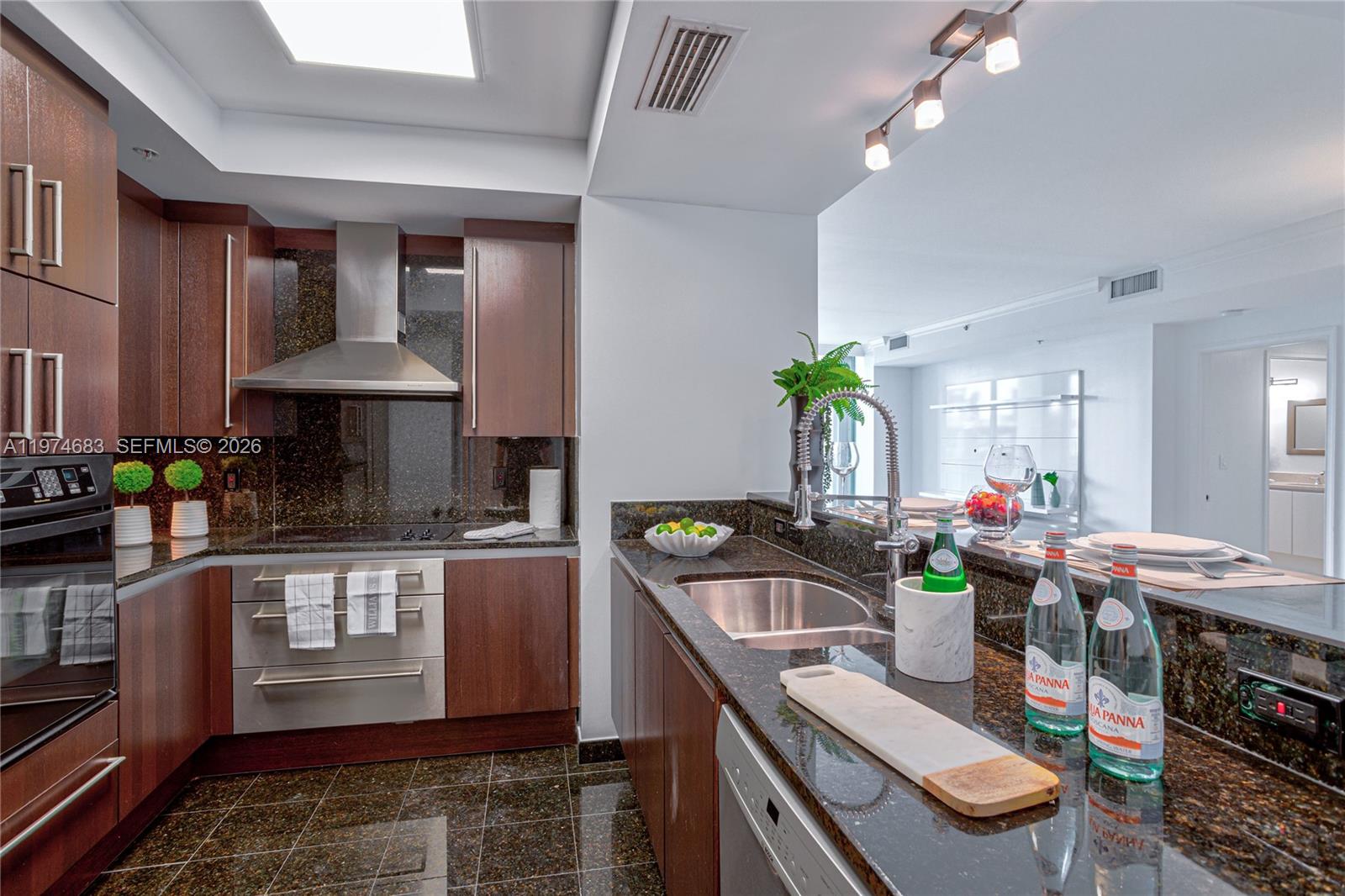 3400 Southwest 27th Avenue, Unit 906 Miami, FL 33133 - Photo 7 of 35 a kitchen with stainless steel appliances granite countertop a sink a stove and a wooden cabinets
