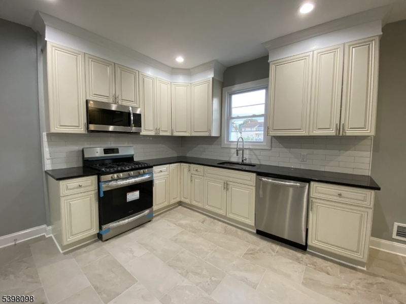 59 West Stewart Street Washington, NJ 07882 - Photo 6 of 22 a kitchen with granite countertop a stove a sink and a microwave