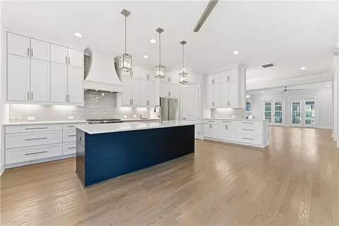 a large kitchen with kitchen island white cabinets and stainless steel appliances