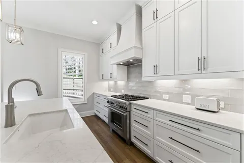 a kitchen with stainless steel appliances granite countertop a stove a sink and white cabinets