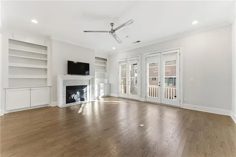 a view of an empty room with wooden floor fireplace and a window