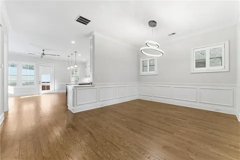 a view of an empty room and kitchen with wooden floor