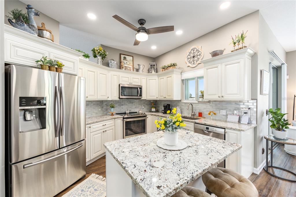 5719 Northwest 25th Loop Ocala, FL 34482 - Photo 24 of 67 a kitchen with stainless steel appliances kitchen island granite countertop a refrigerator a stove a sink a dining table and chairs with wooden floor