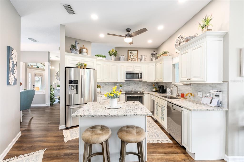 5719 Northwest 25th Loop Ocala, FL 34482 - Photo 25 of 67 a kitchen with stainless steel appliances granite countertop a refrigerator a stove top oven a sink dishwasher and white cabinets with wooden floor