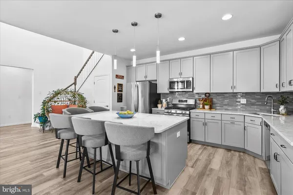 a kitchen with stainless steel appliances kitchen island granite countertop a dining table chairs and white cabinets