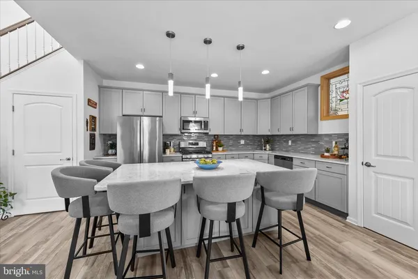a kitchen with stainless steel appliances granite countertop a stove top oven a sink dishwasher and a microwave oven with wooden floor