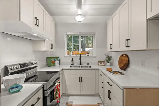 a kitchen with kitchen island white cabinets a sink a stove and a window