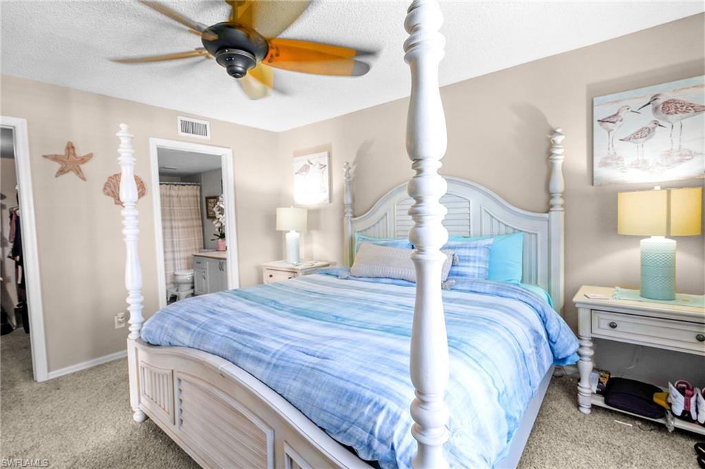 601 Augusta Boulevard, Unit 10 Naples, FL 34113 - Photo 12 of 27 Bedroom with a walk in closet, light colored carpet, a ceiling fan, a textured ceiling, and connected bathroom