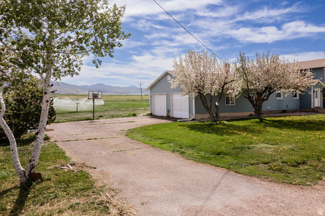19994 South Olson Road Downey, ID 83234 - Photo 31 of 49 View of grassy yard with a garage, a mountain view, and driveway