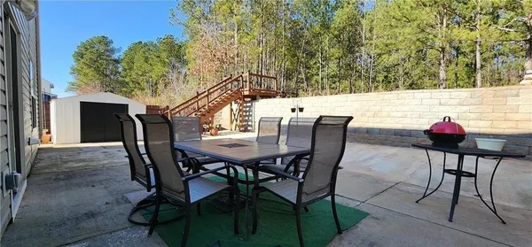 a view of a backyard with wooden fence and large trees