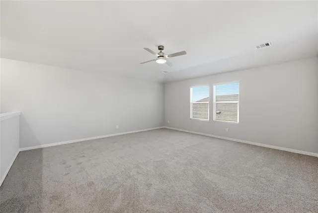 an empty room with a window and a ceiling fan