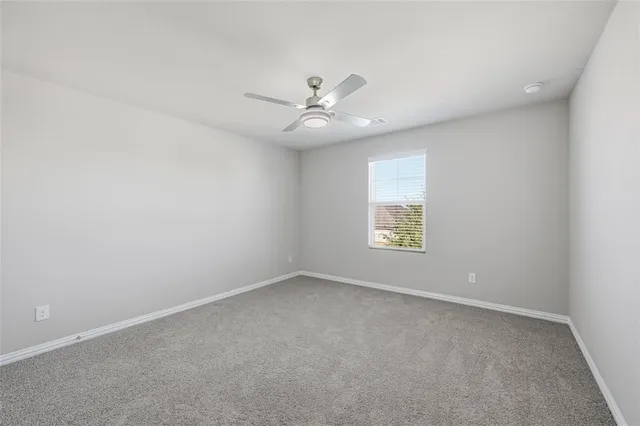 an empty room with a window and a ceiling fan