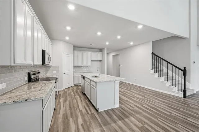 a kitchen with stainless steel appliances granite countertop a stove a sink and a refrigerator