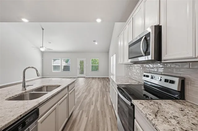 a kitchen with stainless steel appliances granite countertop a sink a stove and a wooden cabinets
