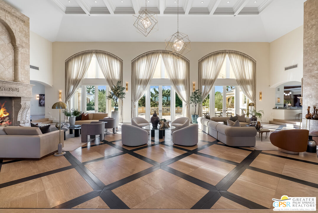 1 St Petersburg Court Rancho Mirage, CA 92270 - Photo 13 of 73 a living room with couches a large dining table and a fireplace with wooden floor