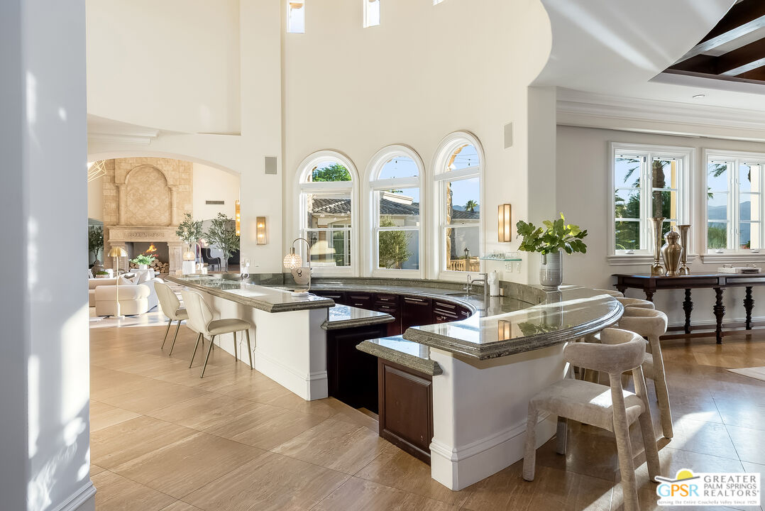 1 St Petersburg Court Rancho Mirage, CA 92270 - Photo 20 of 73 a living room with stainless steel appliances kitchen island granite countertop a stove a sink a refrigerator and a dining table with garden view