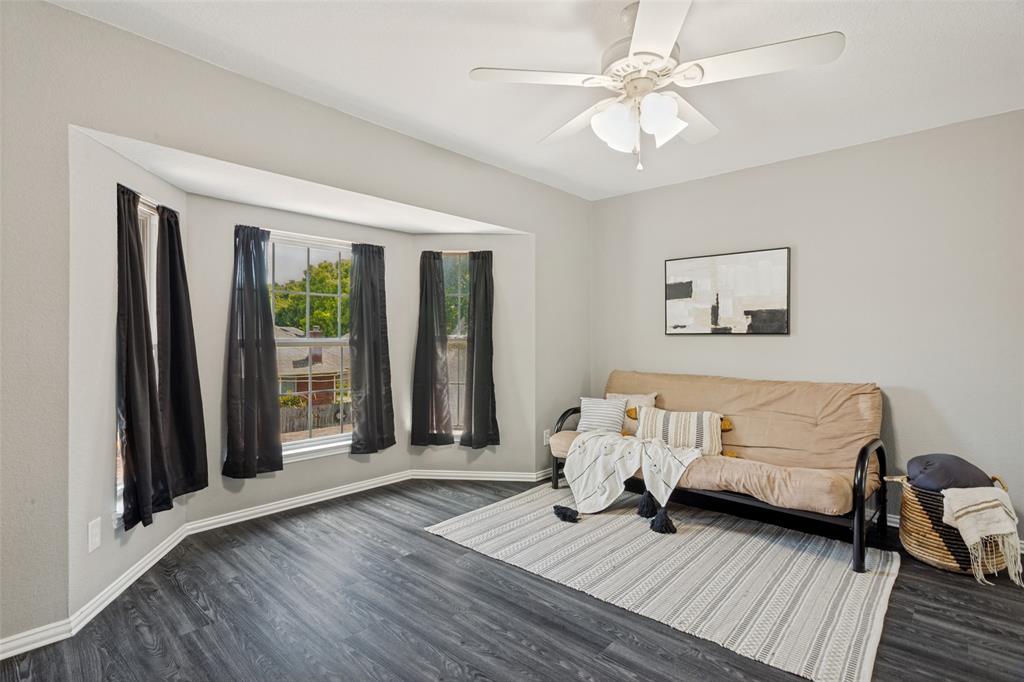 1228 Concho Drive Benbrook, TX 76126 - Photo 22 of 39 Bay window with multiple panes, dark wood-finish flooring, light gray wall paint, and a ceiling fan with integrated lighting