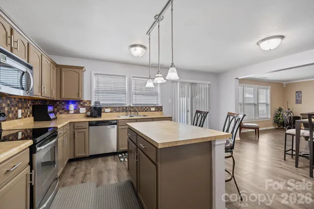 a kitchen with kitchen island granite countertop a stove a sink a dining table and chairs with wooden floor