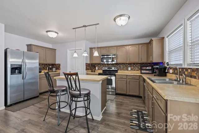 a kitchen with granite countertop a center island stainless steel appliances cabinets and a window