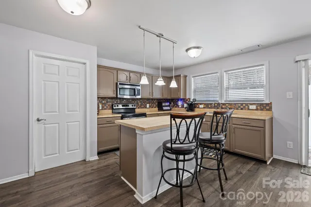 a kitchen with stainless steel appliances granite countertop a stove a sink dishwasher and a refrigerator with wooden floor