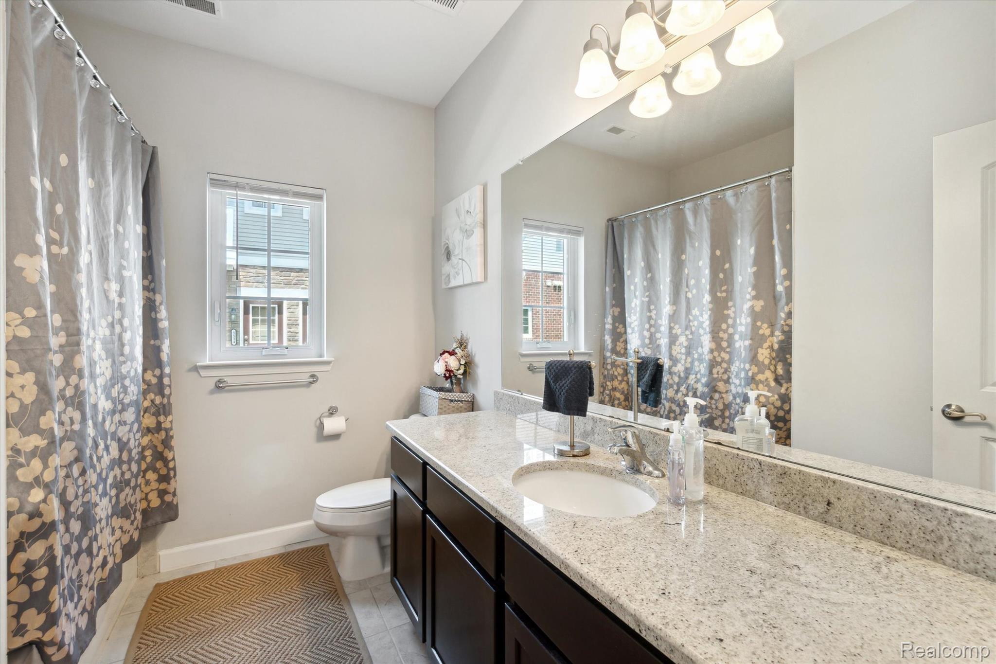 5662 Arbor Chase Drive Ann Arbor, MI 48103 - Photo 18 of 27 Spacious bathroom featuring an expansive vanity with a light granite countertop and dark wood cabinetry