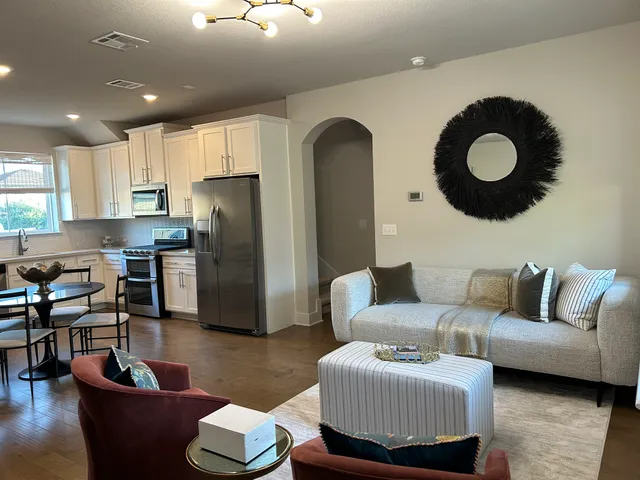 a living room with furniture kitchen view and a wooden floor
