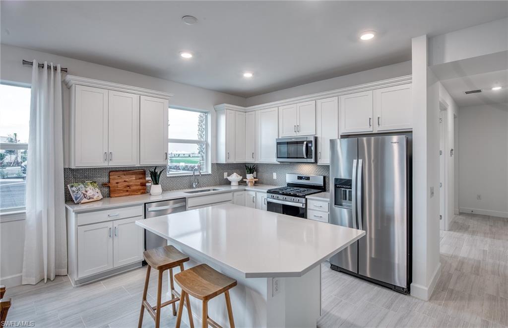 12669 Pyrite Court Alva, FL 33920 - Photo 4 of 13 a kitchen with refrigerator cabinets dining table and chairs