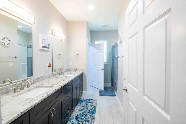 a bathroom with a granite countertop double vanity sink mirror and double