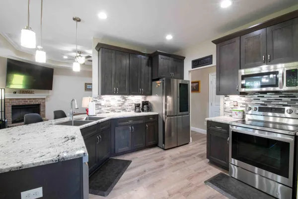 a kitchen with stainless steel appliances kitchen island granite countertop a stove refrigerator sink and microwave