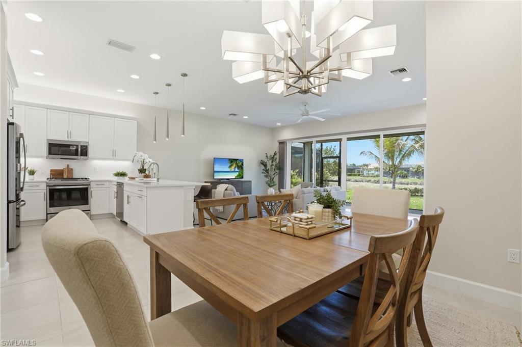 12391 Purple Ficus Way Naples, FL 34120 - Photo 16 of 47 a view of a dining room with furniture a kitchen and chandelier