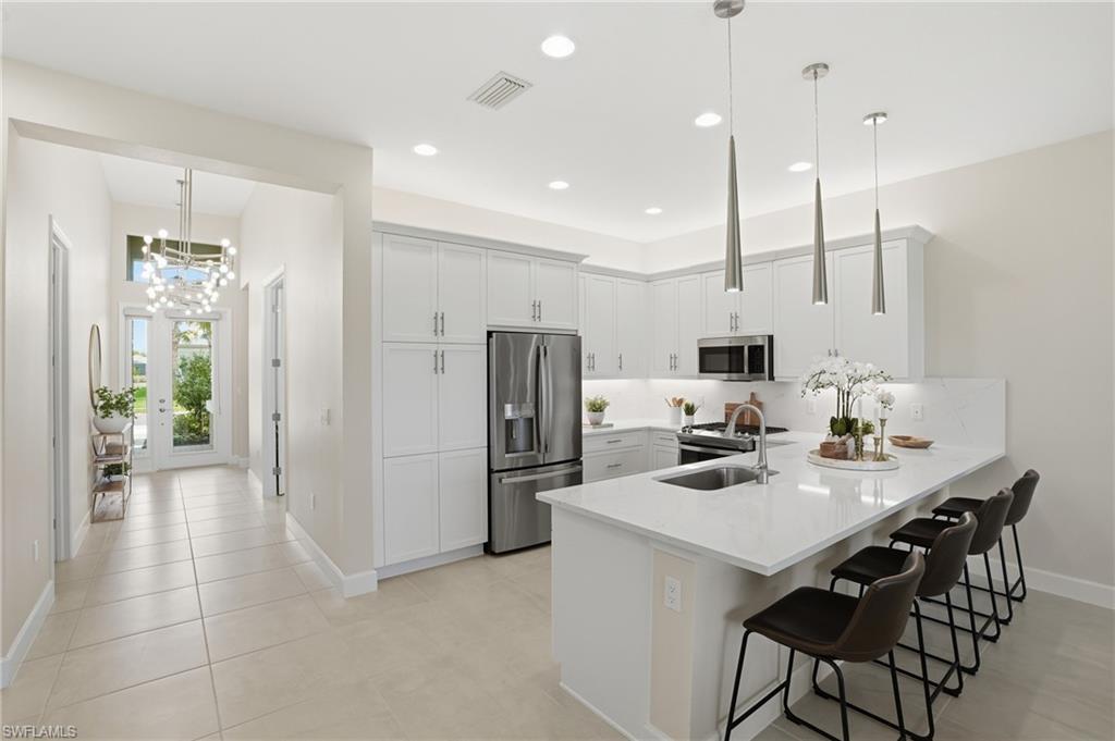 12391 Purple Ficus Way Naples, FL 34120 - Photo 5 of 47 a kitchen with stainless steel appliances a refrigerator a sink a stove a microwave a dining table and chairs