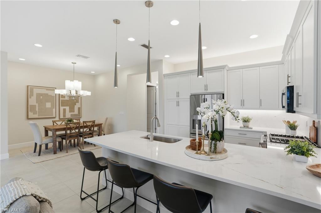 12391 Purple Ficus Way Naples, FL 34120 - Photo 6 of 47 a kitchen with kitchen island a dining table chairs and cabinets