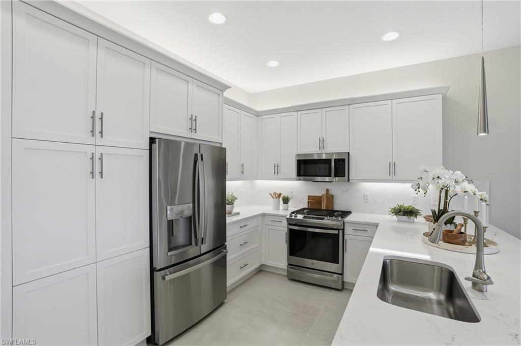 12391 Purple Ficus Way Naples, FL 34120 - Photo 7 of 47 a kitchen with granite countertop a refrigerator and a stove top oven